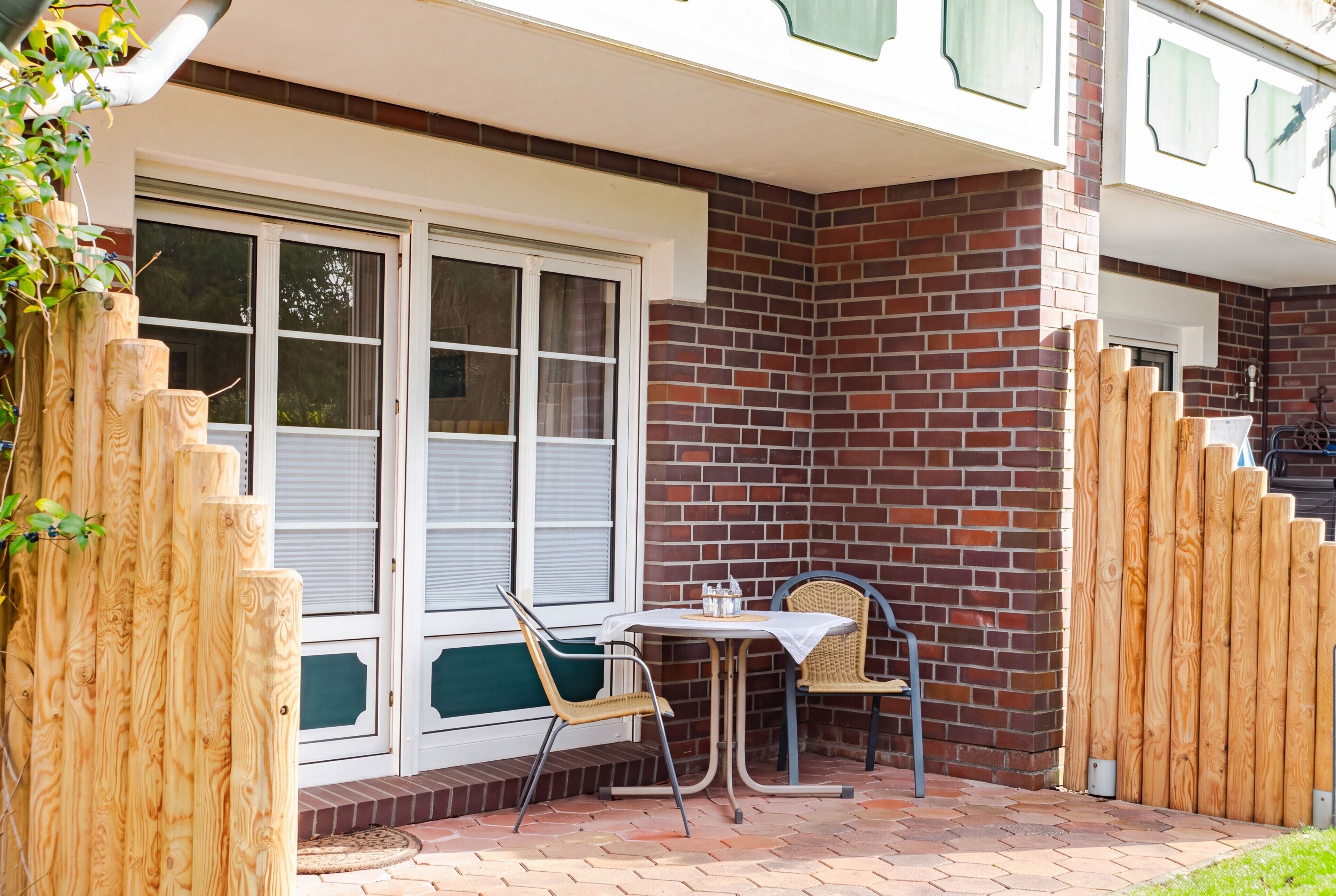Eine Terrasse mit Tisch und Stühlen, eine Ziegelmauer und ein Holzzaun.