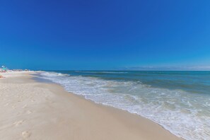 Ein Strand mit blauem Himmel und ruhiger Wellenbewegung.
