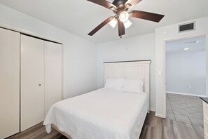 Ein Schlafzimmer mit Bett, Deckenventilator, Kleiderschrank und einer Tür zum Badezimmer.
