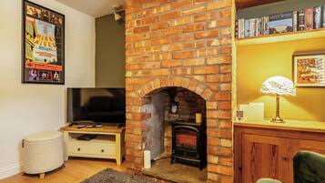 A living room with a brick fireplace, a television, a bookshelf, and a framed picture on the wall.