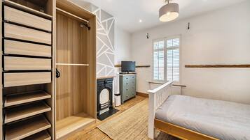 A bedroom with a bed, a wardrobe, a television, and a fireplace.