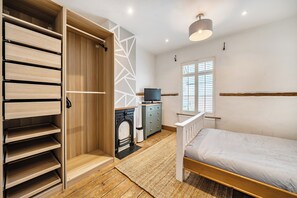 A bedroom with a bed, a wardrobe, a television, and a fireplace. - Quaint Cottage in Charming Evesham (Evesham)