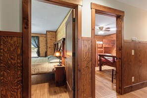 Un interno in legno con un letto, un comodino, una lampada e una ventola a soffitto.