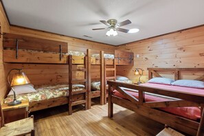 A cabin with three bunk beds, a ceiling fan, and a desk with a lamp. - Millhouse Lodge | Large Group Retreat | Sleeps 30 (Murphy)