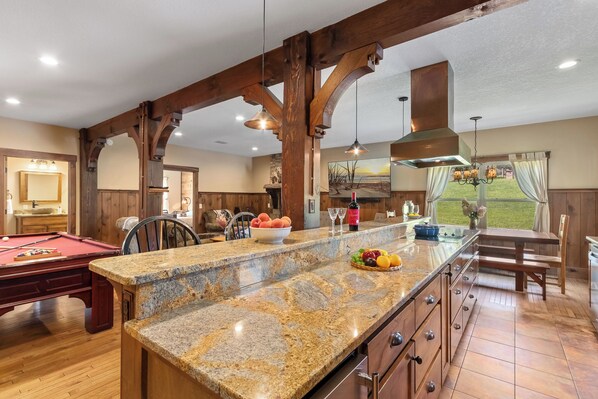 Una cocina amplia con encimeras de granito, vigas de madera y vistas al exterior.