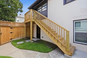 A wooden staircase leading to a deck, a fenced backyard, and a house with a garage. - The Magnolia Suite at One 01 (Savannah)