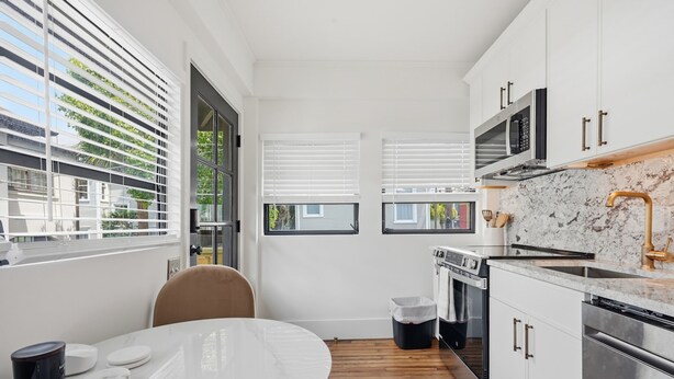 A compact kitchen with a dining area, featuring a round table, a microwave, an oven, and a sink. - The Magnolia Suite at One 01 (Savannah)