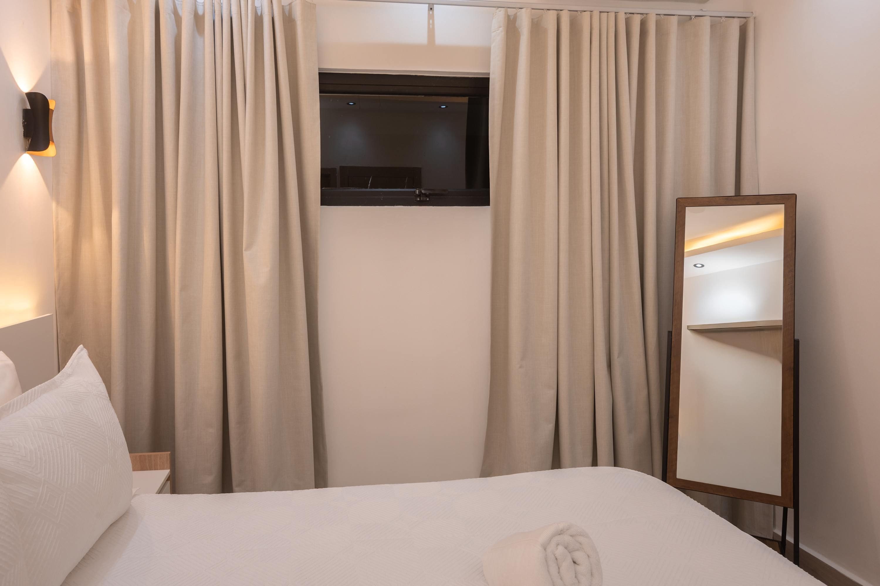 Ein Hotelzimmer mit einem Bett, einem an der Wand befestigten Fernseher und einem Spiegel.