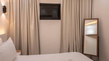 Ein Hotelzimmer mit einem Bett, einem an der Wand befestigten Fernseher und einem Spiegel.