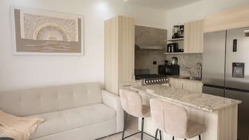 Una cocina moderna con una isla central, taburetes de bar, estufa integrada y refrigerador.