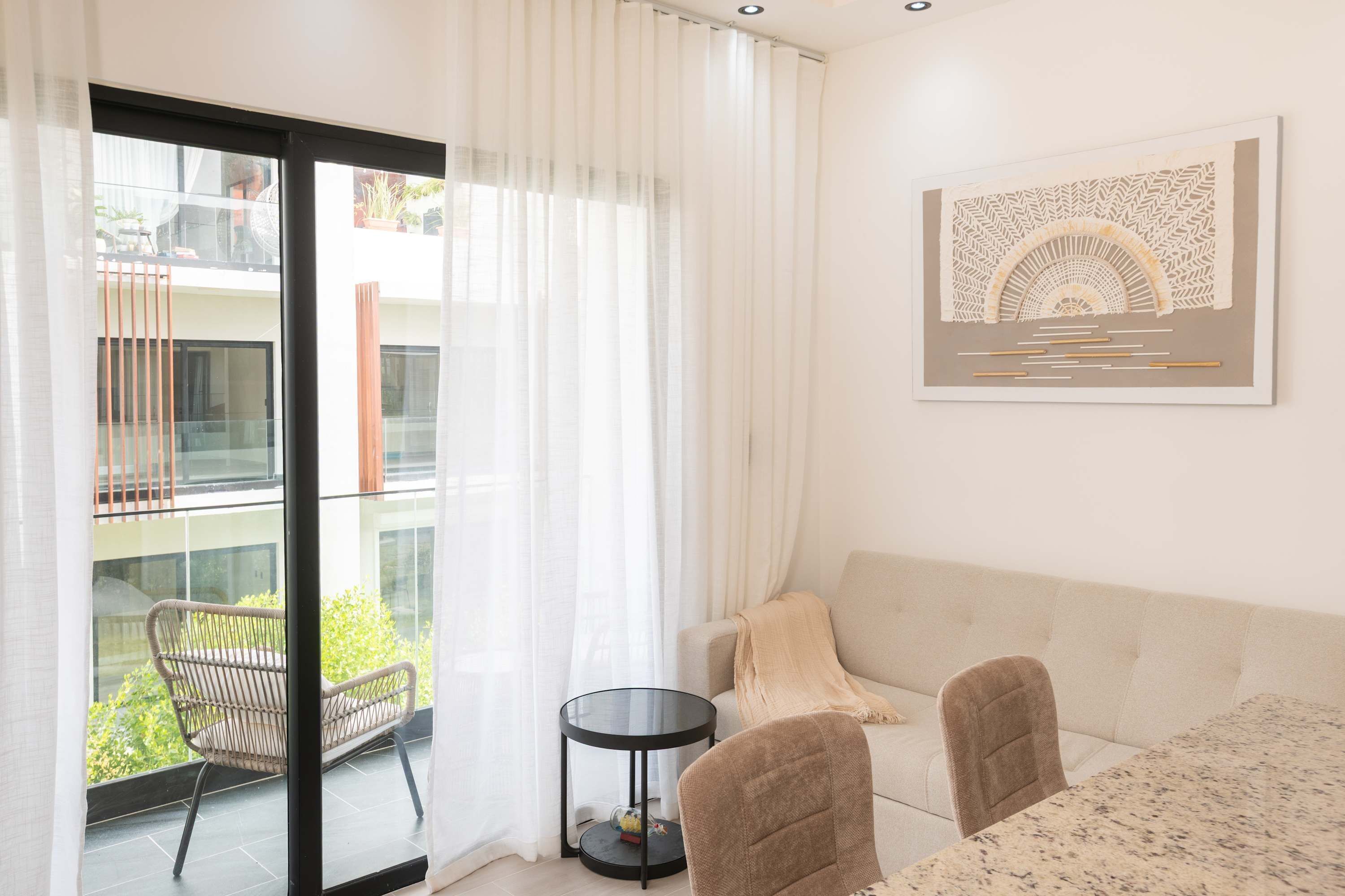Ein modernes Wohnzimmer mit einer Couch, zwei Sesseln, einem Glastisch und einem Balkon mit einem Sessel.