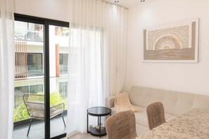 Un saló modern amb un sofà, dues butaques, una taula de vidre i un balcó amb una cadira.