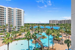 A resort with multiple swimming pools surrounded by palm trees and lounge chairs. - Paradise at The Palms | Gulf Views, Resort Pool & Beach Gear (Destin)