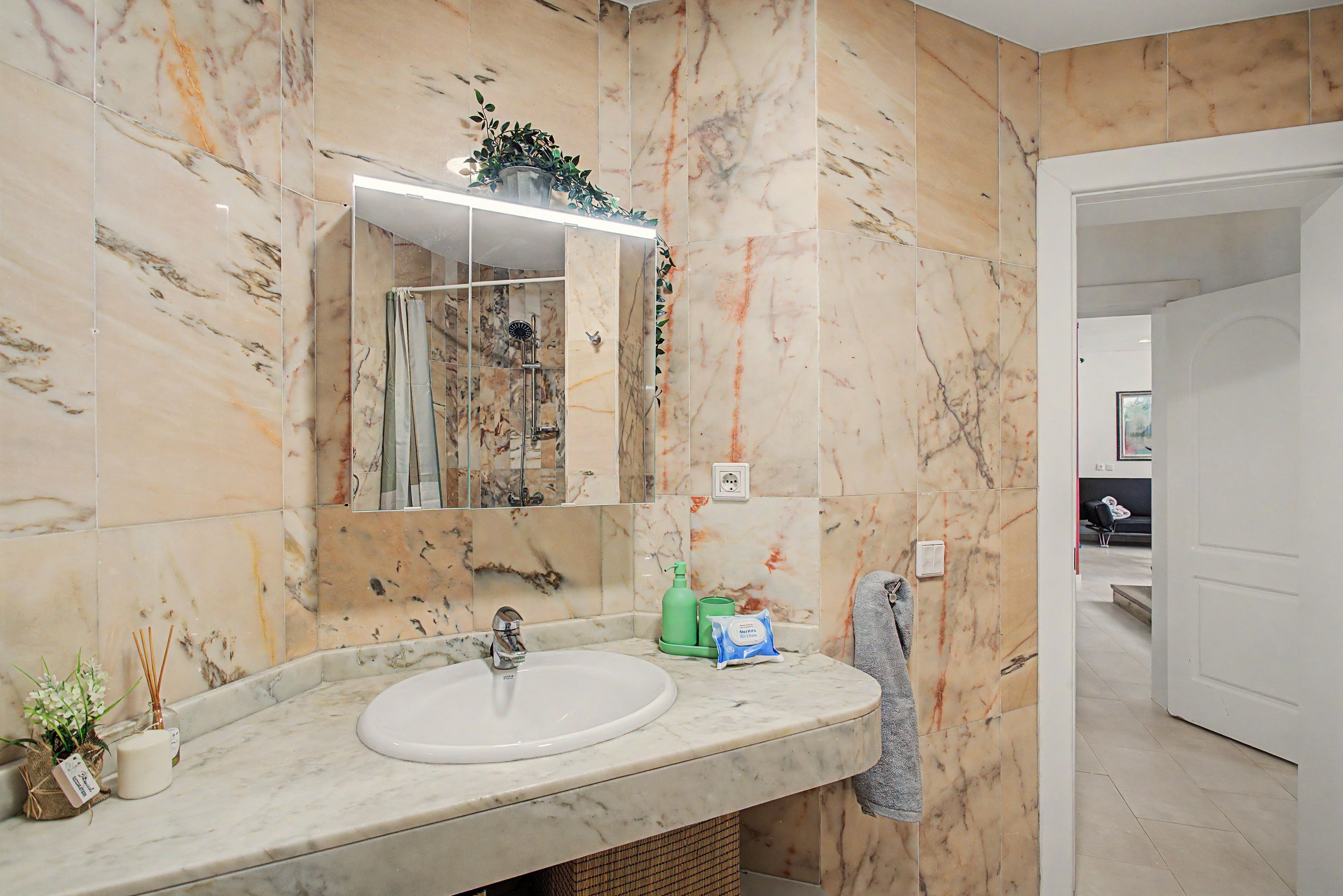 Une salle de bain avec un lavabo en marbre, une douche en verre et un miroir.
