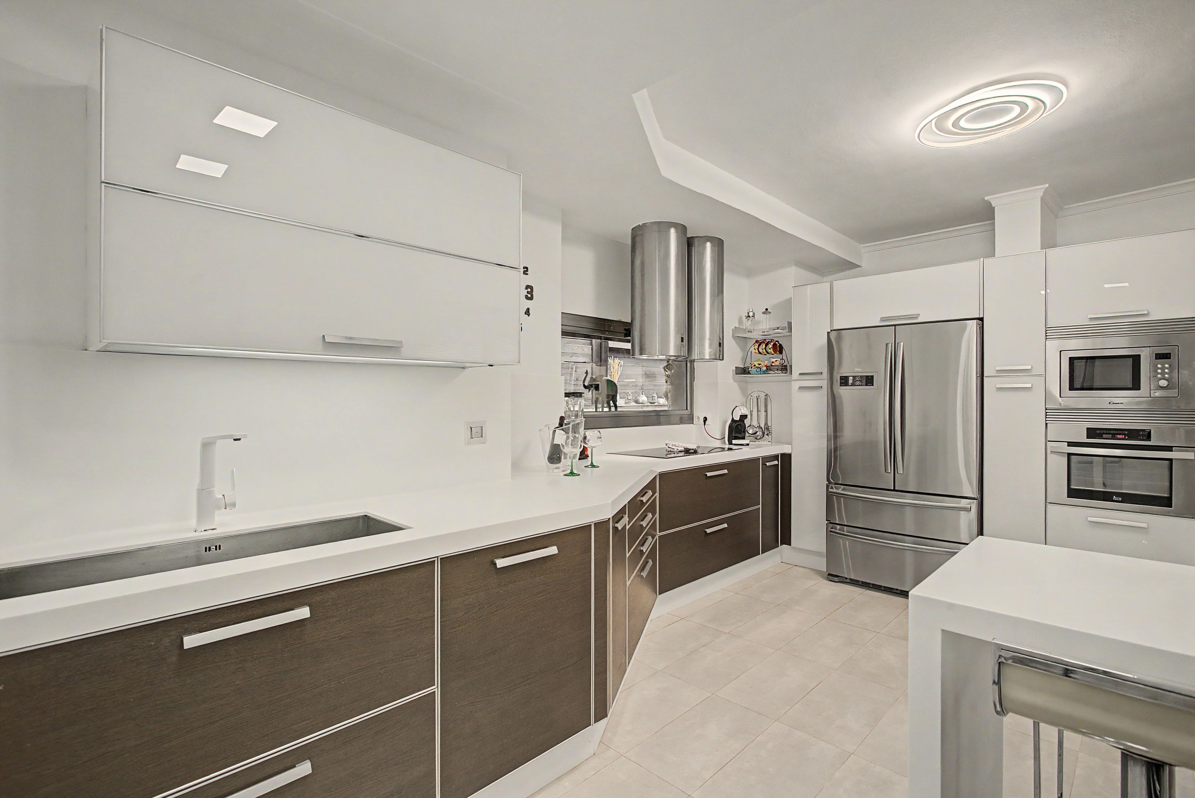 Una cocina moderna con electrodomésticos de acero inoxidable, un lavamanos doble y una isla grande con cajones.