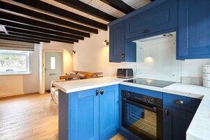 Uma cozinha moderna com armários azuis, forno embutido e cafeteira.