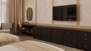 Habitación de hotel con dos camas, un escritorio con una silla, un televisor y un espejo grande.