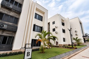 Ein modernes Apartmenthaus mit Balkonen, Klimaanlagen und einem gepflegten Rasen.