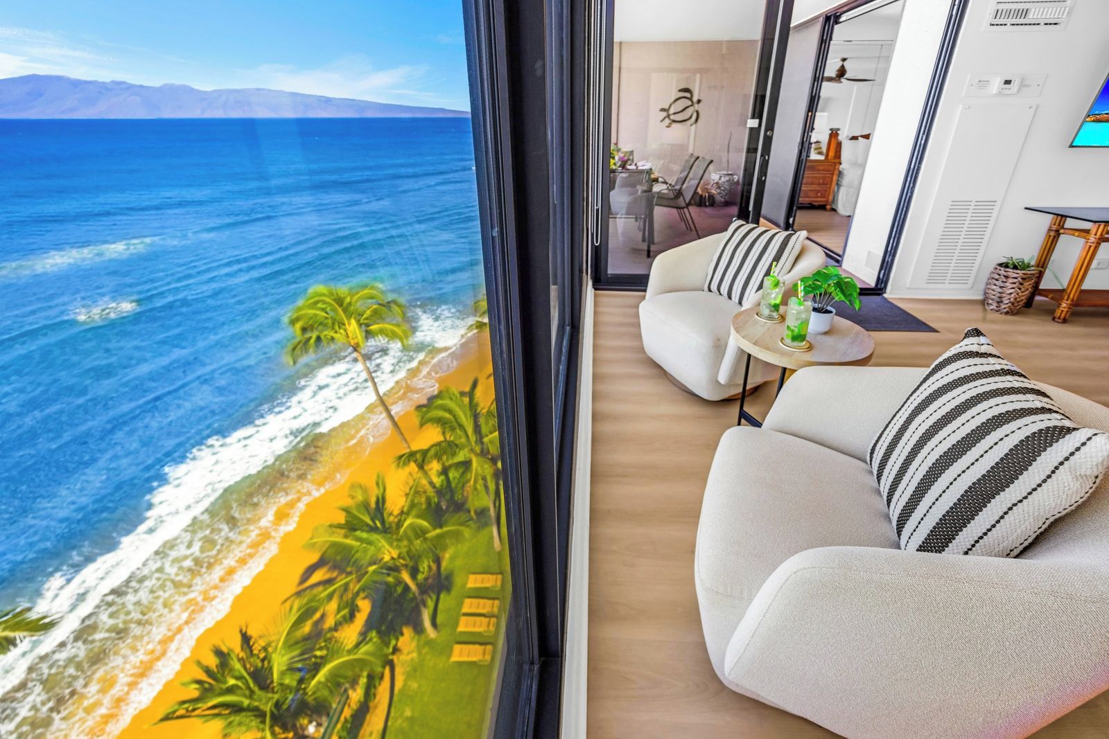 Ein modernes Wohnzimmer mit einem großen Fenster mit Blick auf Strand und Meer.