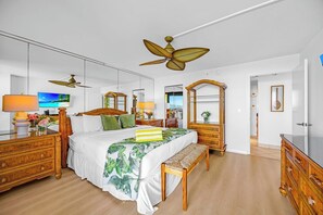 Ein Hotelzimmer mit einem Bett, Holzmöbeln, einem Deckenventilator, einem Fernseher und einem Spiegel.