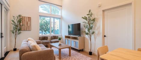 A modern living room with a sofa set, a coffee table, a TV, and a dining table.