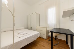 Ein Schlafzimmer mit Bett, Schreibtisch, Kleiderschrank und Stuhl.