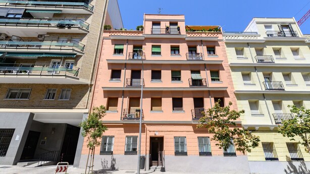 A multi-story residential building with balconies, a gated entrance, and a clear sky. - (MGU272D) 2-bedroom apartment in Chamberí (Madrid)