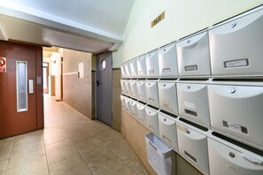 A hallway with a row of mailboxes on the right, a door labeled 'BAJO' on the left, and a no-smoking sign above it. - (MGU272D) 2-bedroom apartment in Chamberí (Madrid)