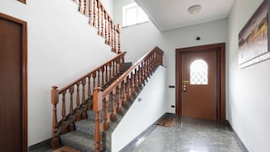 A staircase with wooden balusters leading to a landing, a door with a window, and a doormat on the floor.