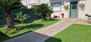 A residential property with a paved pathway, a green lawn, and a door with a window. - castelbarco house (Rome)