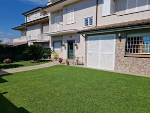 A two-story residential building with a well-maintained lawn and a front door. - castelbarco house (Rome)