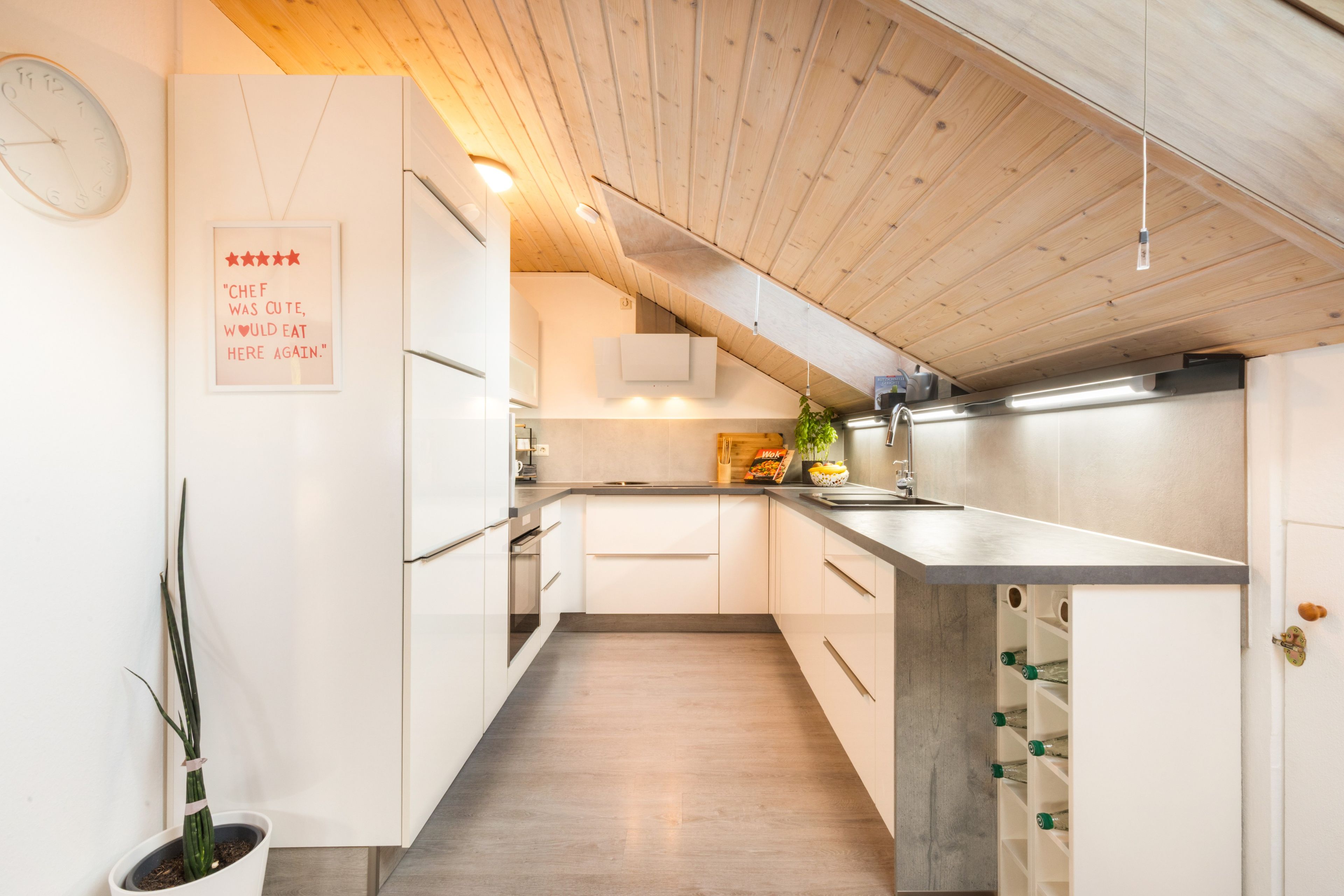 A modern kitchen with white cabinetry, a wooden ceiling, and a kitchen island.