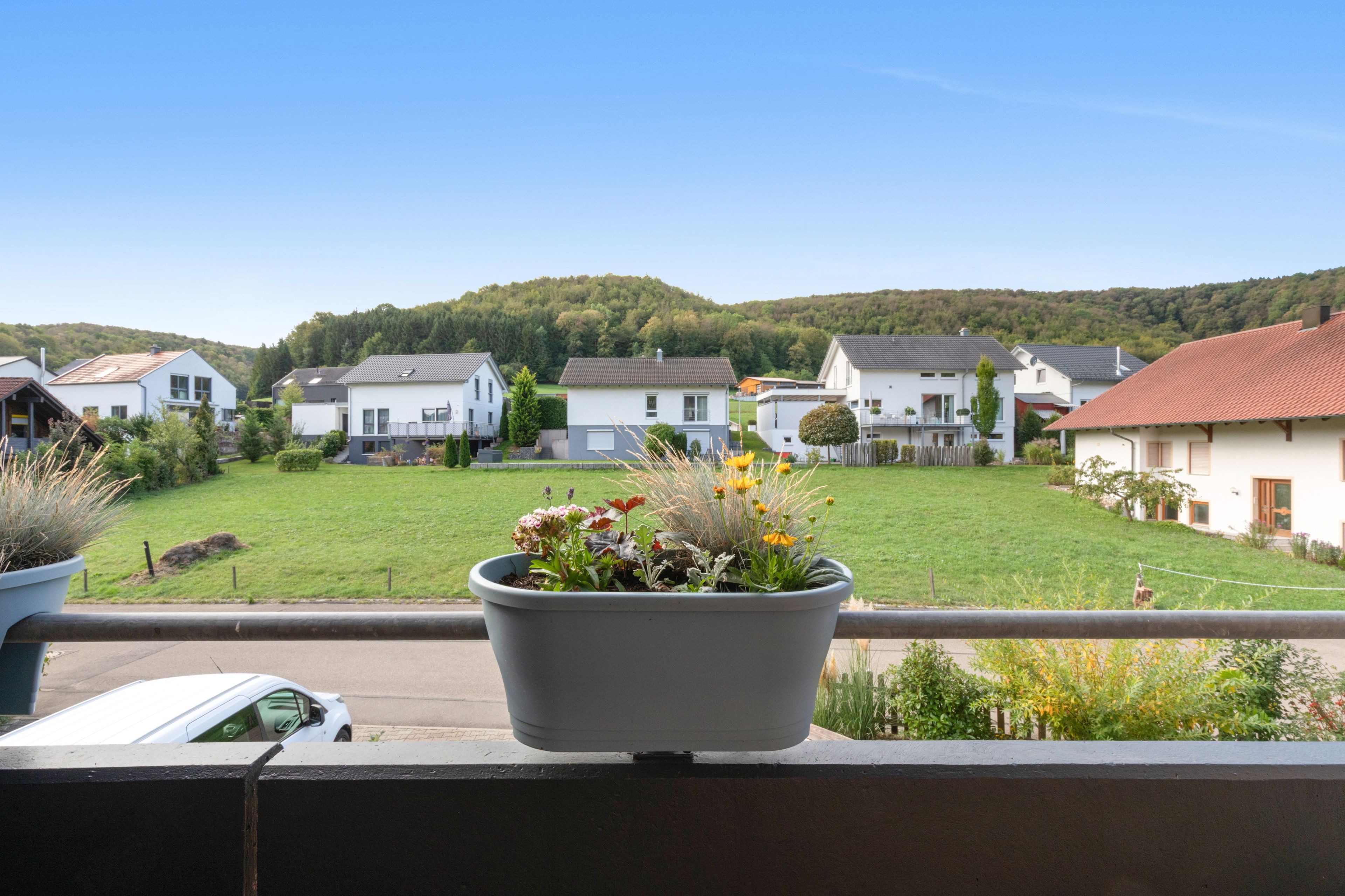 Un quartier résidentiel avec des maisons, une pelouse et une colline en arrière-plan.