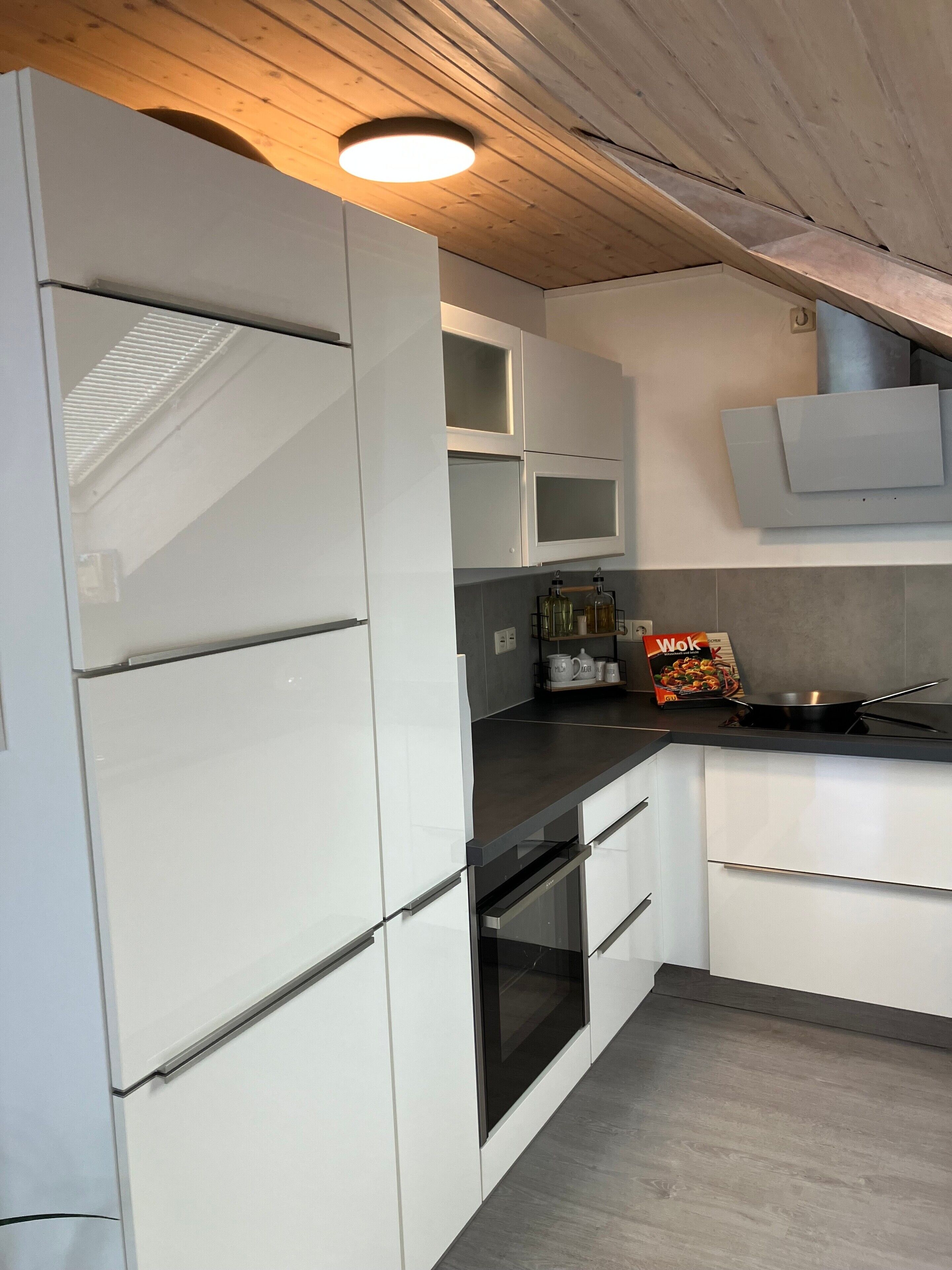 Una cocina moderna con armarios blancos, horno integrado y estufa.