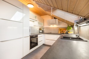 Una cucina moderna con mobili bianchi, forno integrato e lavello in acciaio inossidabile.