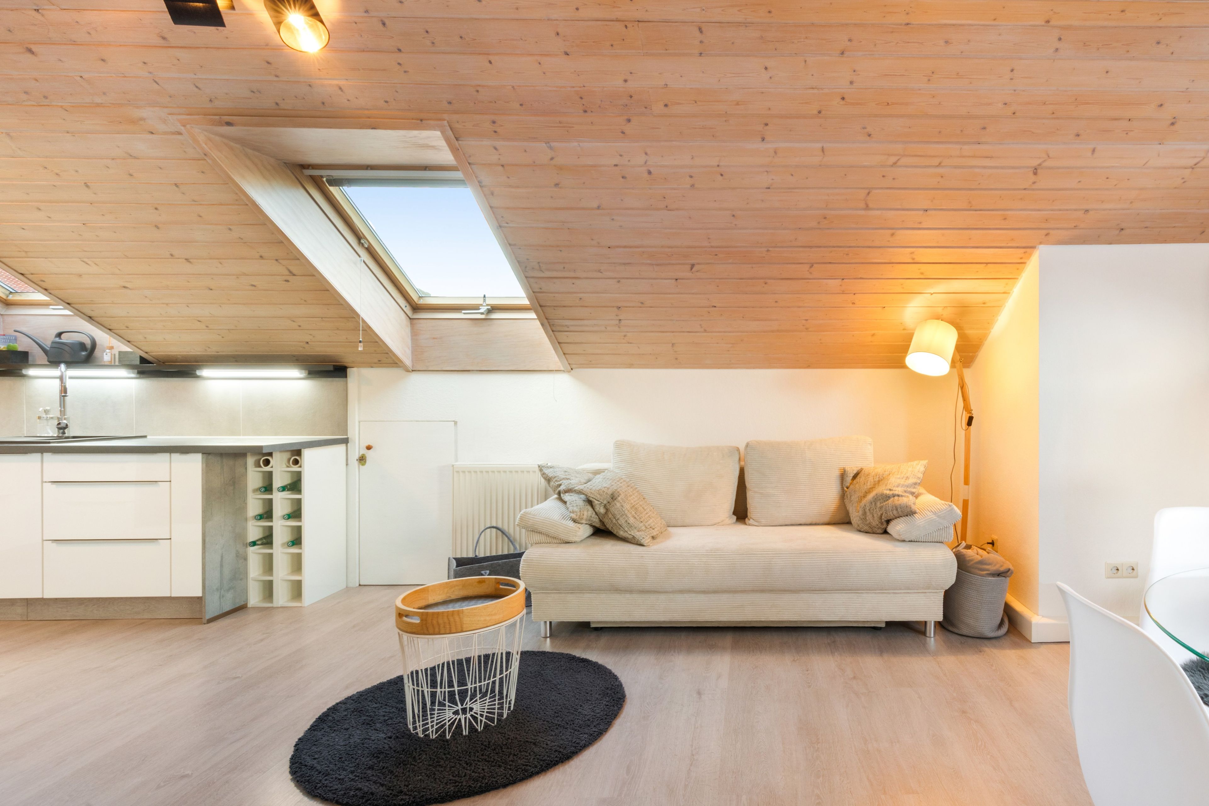 Une chambre de style loft moderne, dotée d’une fenêtre de toit, d’un canapé, d’une table de chevet et d’un radiateur.