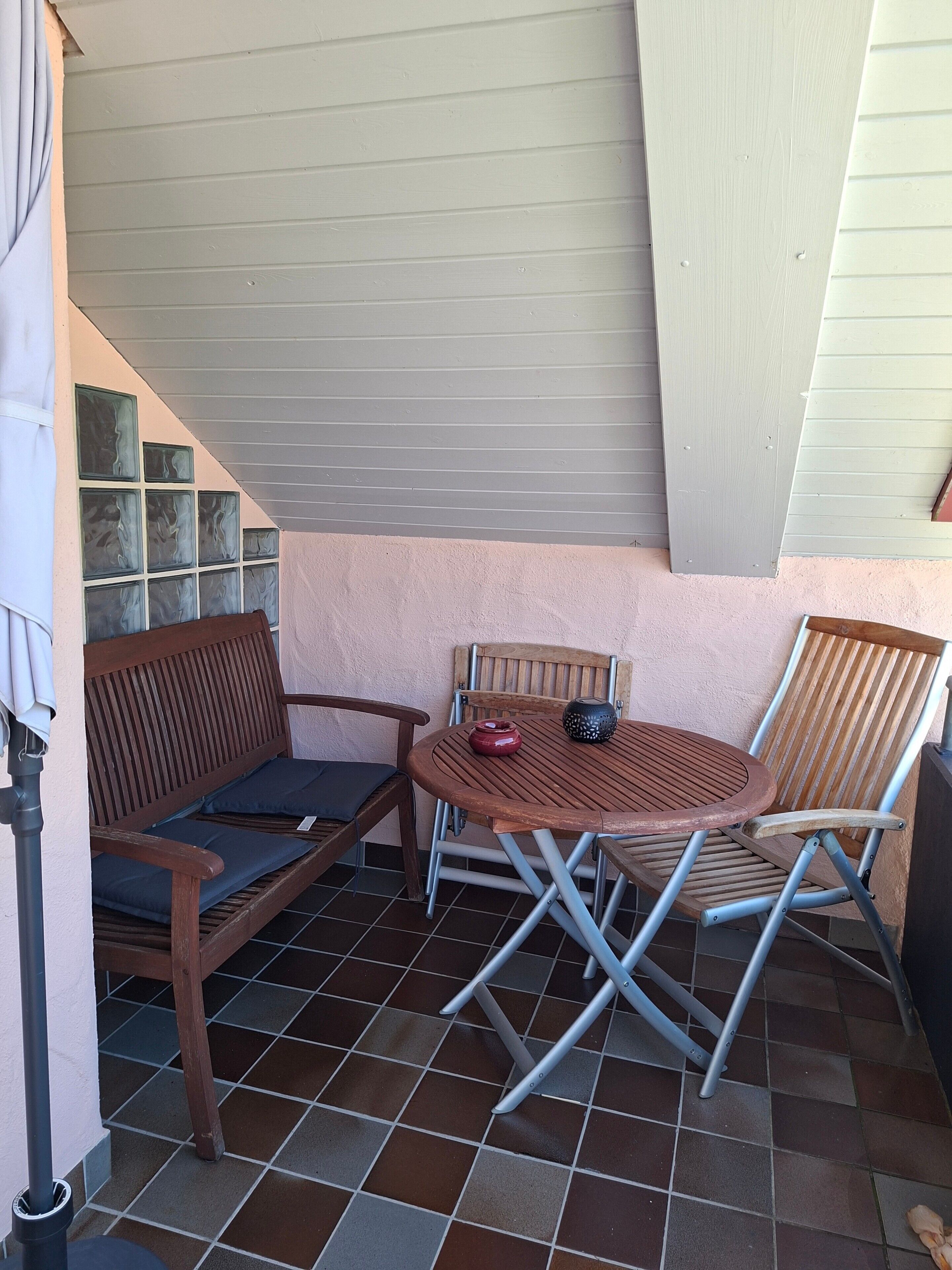 Un patio con un banco de madera, una mesa plegable y una silla.