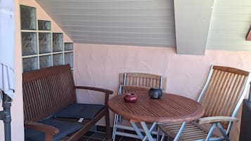 Un patio con un banco de madera, una mesa plegable y una silla.