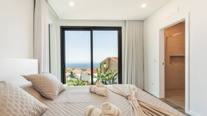 Una habitación de hotel con una cama grande, vista al mar y un balcón.