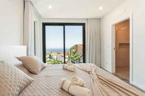 A hotel room with a large bed, a view of the sea, and a balcony.