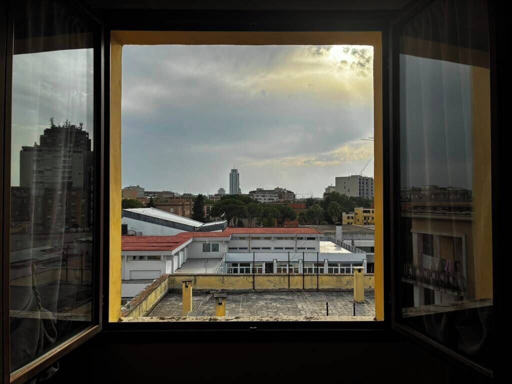 Vista a través de una ventana que muestra un paisaje urbano, con edificios y cielo despejado.