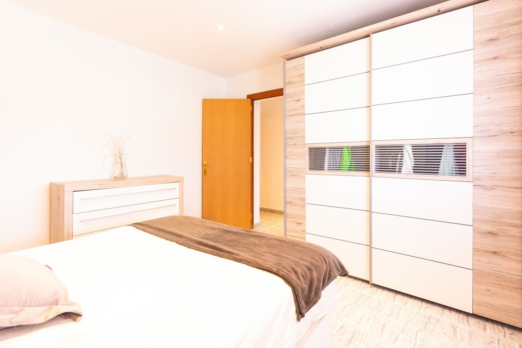 Ein Schlafzimmer mit einem Bett, einem Kleiderschrank und einer Tür zu einem anderen Raum.