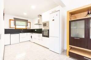 A modern kitchen with white cabinetry, a built-in oven, a microwave, and a dishwasher.
