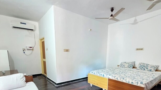 Una habitación con cama, mesita de noche, aire acondicionado y ventilador de techo.