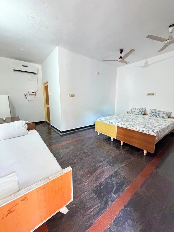 A room with a bed, a bedside table, an air conditioning unit, and a ceiling fan.
