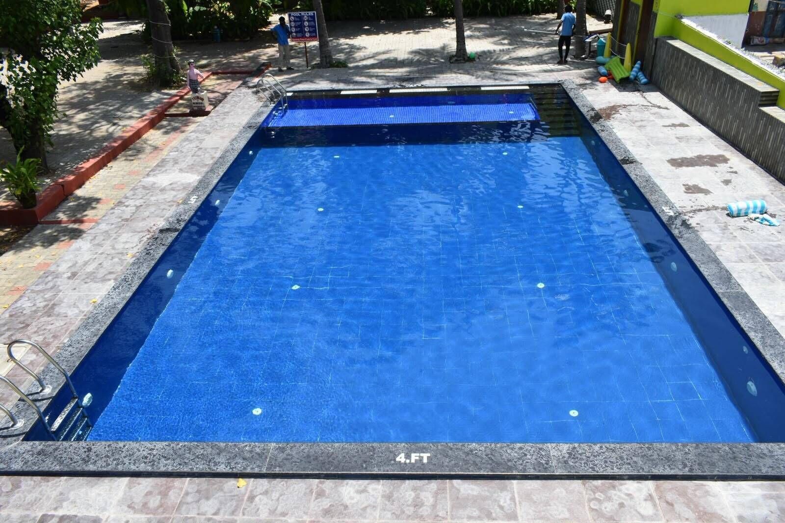 Et rektangulært swimmingpool med flisekant og en dybdemarkør der angiver 4 fod.