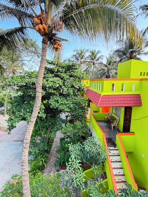 A brightly colored building with a red roof, surrounded by lush greenery and palm trees.