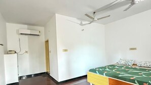Una habitación con cama, escritorio, ventilador de techo y aire acondicionado.