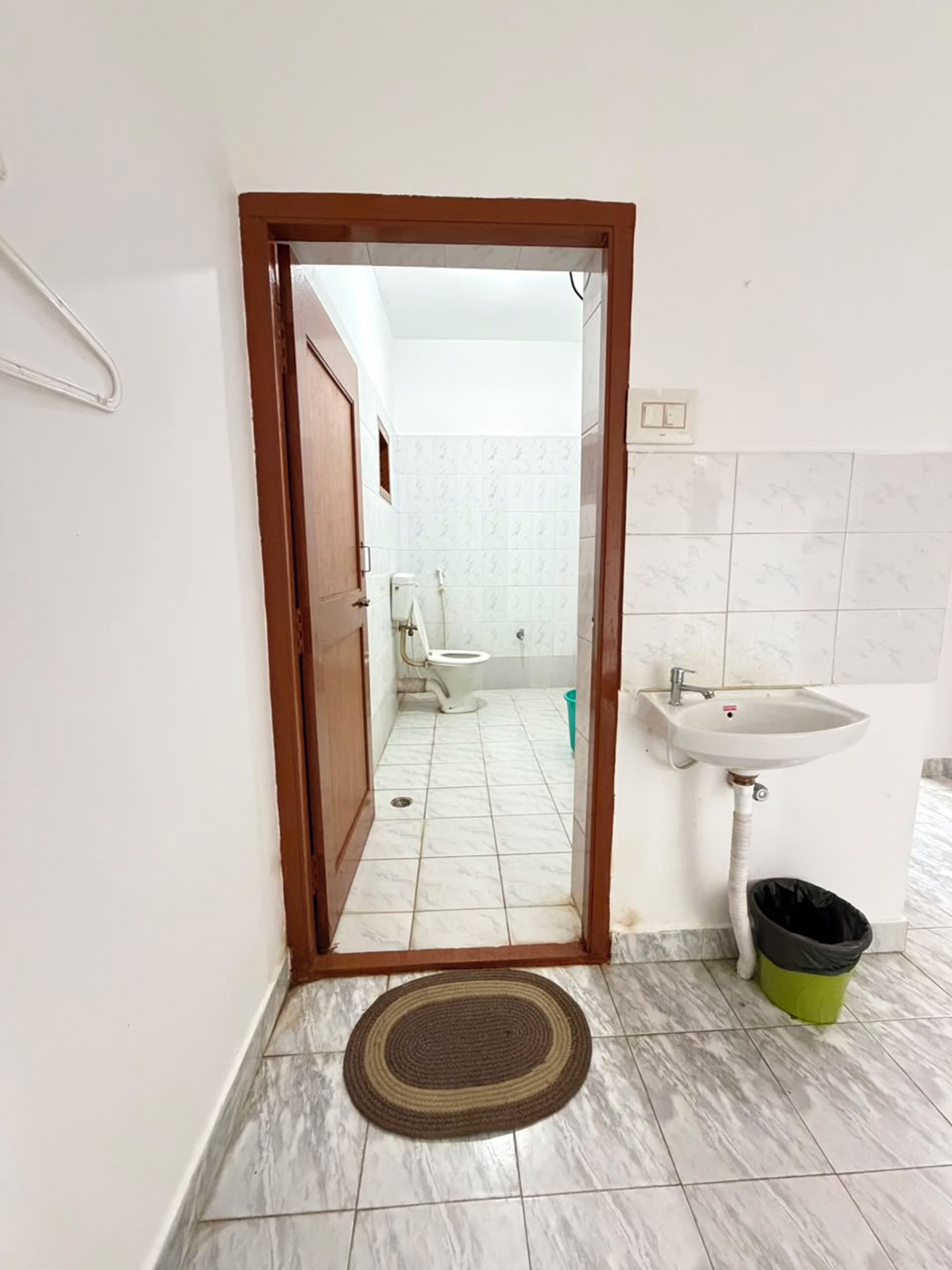 A bathroom with a toilet, sink, and a trash bin.