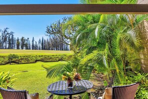 A patio with a round table, chairs, and a view of a manicured lawn and trees. - Kapalua Ridge | 3 Ocean View Villas, Sleeps 16 | Car Incl. w/ 6+ Nights | ML-4256 by KBM (Lahaina)